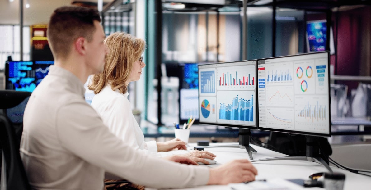 Zwei Menschen im Büro am Computer schauen sich Statistiken an